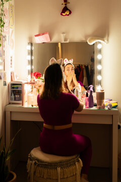 young woman Applying Facial Serum sitting in a vanity desk 