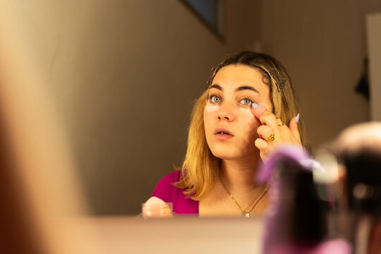 teenager girl  applying concealer during makeup routine 