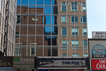 Fototapeta premium reflection of architecture in mirror glass windows located near The Fox: A Firkin Pub (51 Eglinton Avenue East in Toronto, Canada)