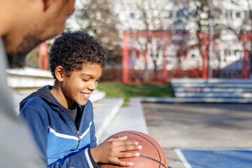 Tired father and son spending leisure time at basketball court