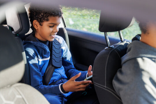 Smiling boy playing online game on smart phone while sitting in car