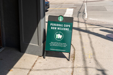 Obraz premium sidewalk sign outside a Starbucks Coffee location on Eglinton Avenue West in Toronto, Canada (