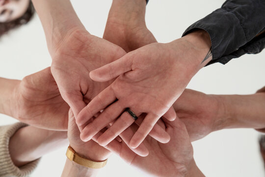 Crop faceless people stacking hands together