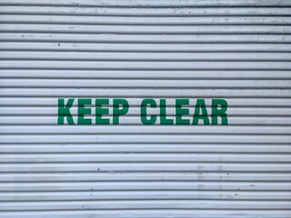 metal garage door with 'keep clear' in green letters in centre.