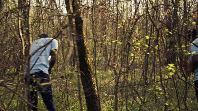 Civilian search party beginning the manhunt within the forest area, screaming the missing person name and tracking his steps. Rescuers group looking for clues, emergency mission. Camera B.