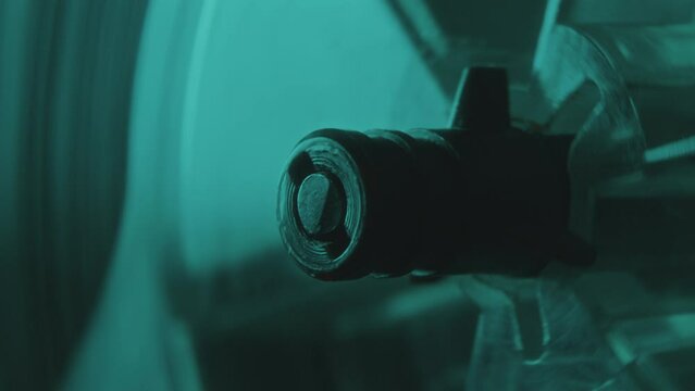 Extreme close-up shot of reel-to-reel tape recorder spindle spinning as music playing in dark room with neon illumination
