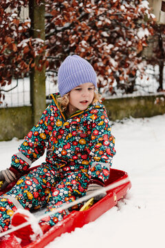 Happy girl in the snow with a sledge