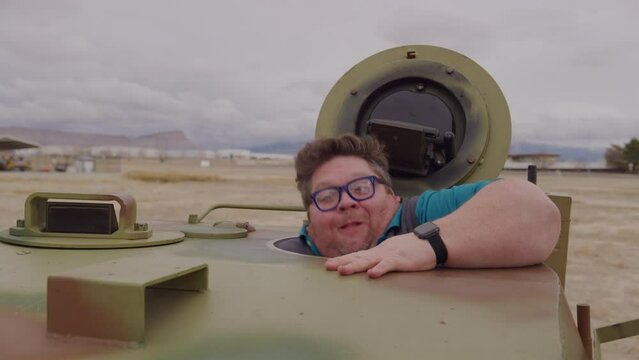 Funny, large man exiting and entering small tank - medium shot