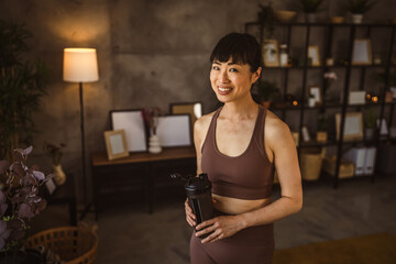 Japanese woman hold supplement shaker take a break from training