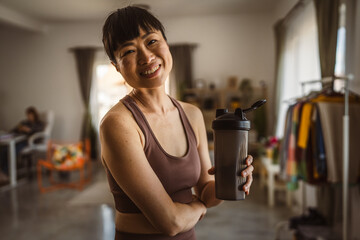 Japanese woman hold supplement shaker take a break from training