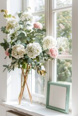 Fototapeta na wymiar Pink and white hydrangeas in a vase on table, a small green picture mockup frame, against the window 