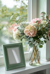 Pink and white hydrangeas in a  vase on table, a small green picture mockup frame, against the window 