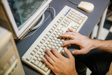 Hands on the keys of a vintage computer keyboard from the 90s