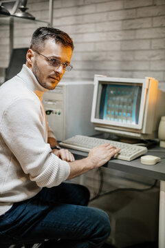 A focused computer programmer in the 90s with his hand on the keyboard
