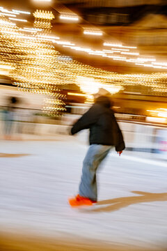 A lonely person rides on an outdoor ice rink in the evening lights