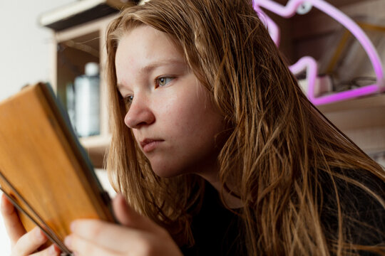 Teenager girl looks at her skin in mirror