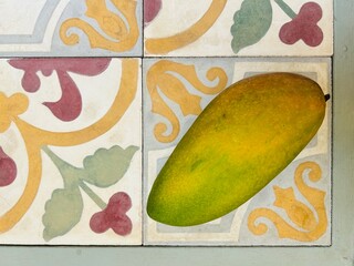 bright yellow and green mango on a colorful tile - travel texture in Cambodia