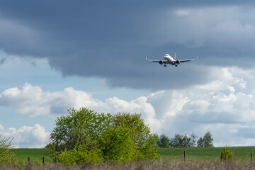 Samolot nad łąką i drzewami, na tle chmur   A Plane over meadow and trees, against the background of clouds © Adrian White