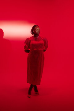 Curvy woman modeling in a dress and red lightning studio
