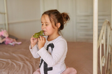 Child, toy and girl kissing frog in bedroom for fairytale, happiness or playing in family home....