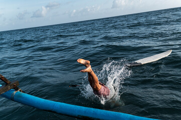 Surfer leap from a boat into the sea