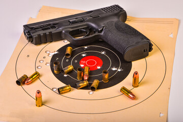 Unidentified handgun with spent shell casings and live rounds on target with holes. Conceptual image of what gun control should be.