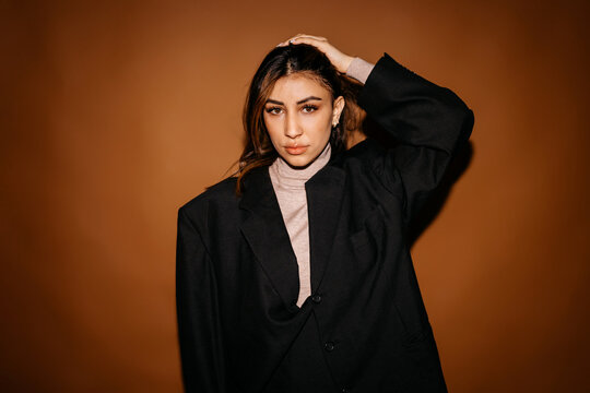 Self assured woman in suit touching hair in studio