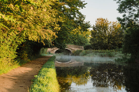 Sunlight on canal path and mist at sunrise