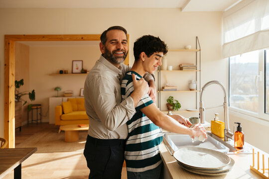 Father and son washing dishes at home