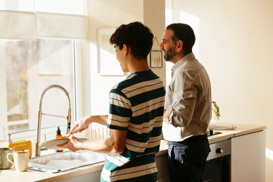 Father and son washing dishes at home
