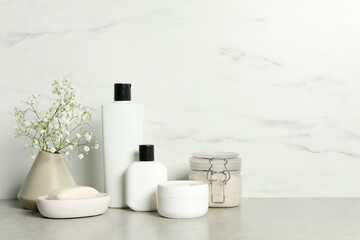 Bath accessories. Personal care products and gypsophila flowers in vase on gray table near white...
