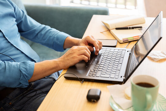 Unrecognizable man works on his laptop from his home office