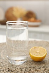 Glass with clear water and half of lemon on table in kitchen