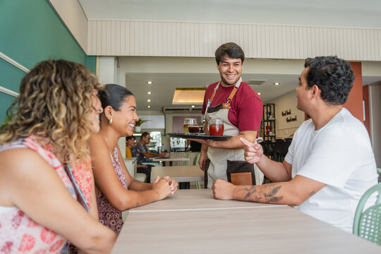 Waiter Serving Food to a Group of Friends in a Restaurant