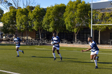 Three African American young male athletes training on sunny rugby field outdoors