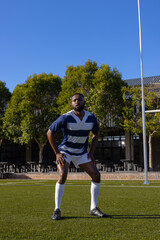 African American young male athlete standing on a rugby field outdoors, hands on hips