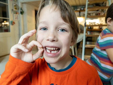 Portrait of a blonde boy showing his fallen tooth