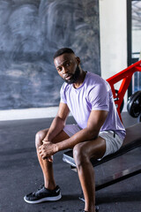 Fototapeta na wymiar African American young male athlete sitting on a bench in a gym, copy space