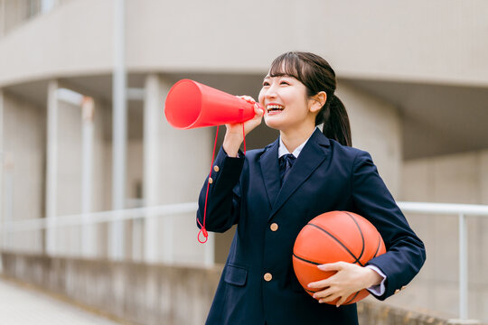 校舎の前でバスケットボールを持つ女子中学生・女子高生（部活・スポーツ・運動部・バスケ部）
