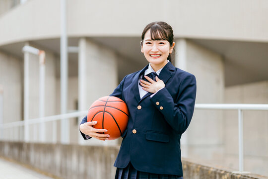 校舎の前でバスケットボールを持つ女子中学生・女子高生（部活・スポーツ・運動部・バスケ部）
