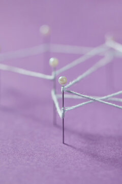 Network connection made of white thread and straight push pins