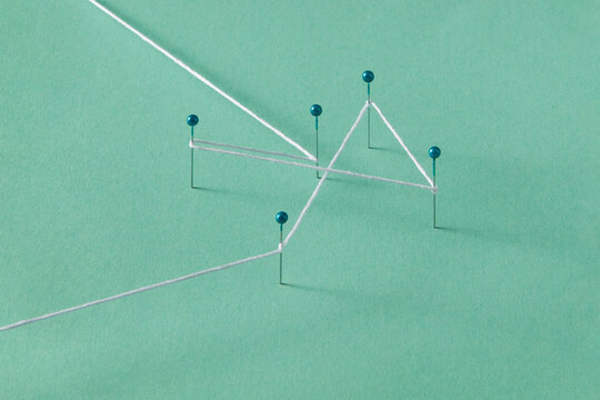 Five stationery pins connected with white thread in studio