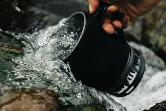 Man's hand scoops water into a bowl.