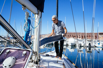 Mature man on sailboat carrying solar panel