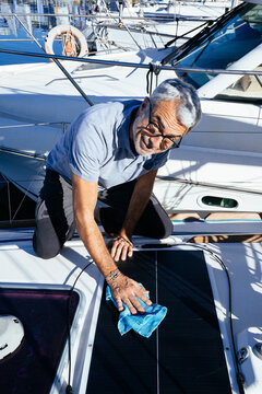 Happy mature man cleaning boat solar panel