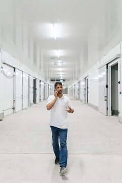 Man speaking on smartphone in warehouse corridor