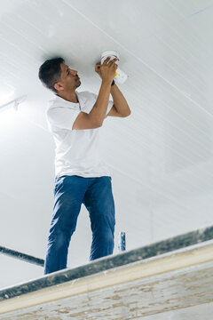 Focused man standing on scaffold platform while mounting camera
