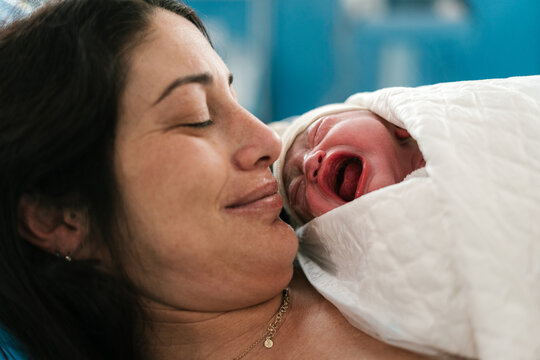 Positive mother resting with crying newborn baby