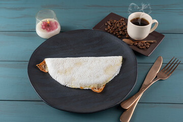 Melted mozzarella cheese tapioca, next to a cup of black coffee_blue wood background. Traditional Brazilian food_1.
