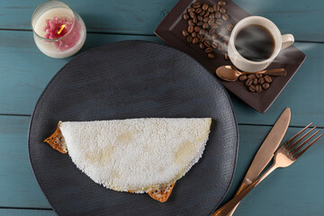 Melted mozzarella cheese tapioca, next to a cup of black coffee_blue wood background. Traditional...